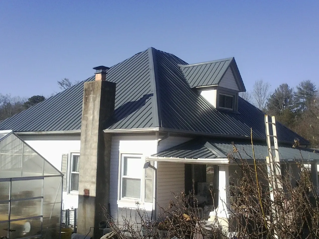 Dark blue standing seam metal roof on a white farmhouse with dormer — Slate & Tile Roof Repair by Roofing Brothers in Cumberland Furnace