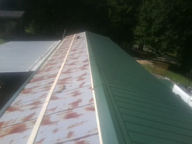 Old rusted panels beside newly installed green metal roofing — Wind Damage Roof Repair by Roofing Brothers in Cumberland Furnace