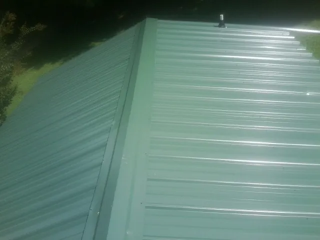 New green metal panels meeting at the ridge of a roof — Flat Roof Repair work by our crew in Cumberland Furnace