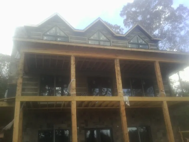 Dormers and porch framing on a large log home under construction — Roof Coating work by our crew in Cumberland Furnace