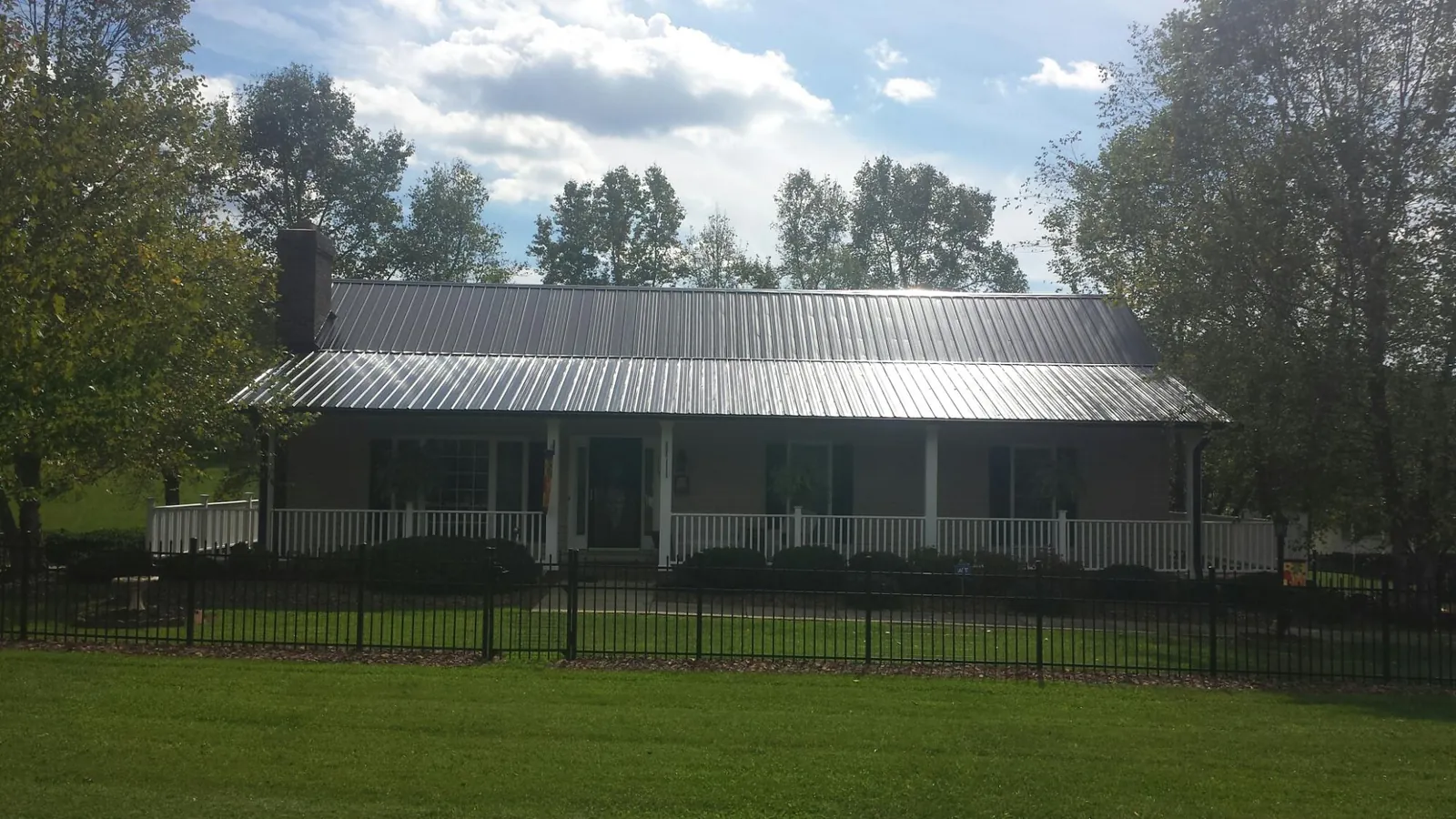 Gray metal roof on a brick ranch with a full width front porch — Gutter Guard Installation work by our crew in Cumberland Furnace