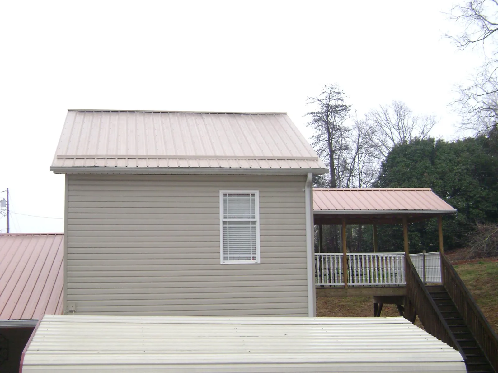Tan metal roofs on a two story addition and attached porch, from a Roof Replacement job in Cumberland Furnace