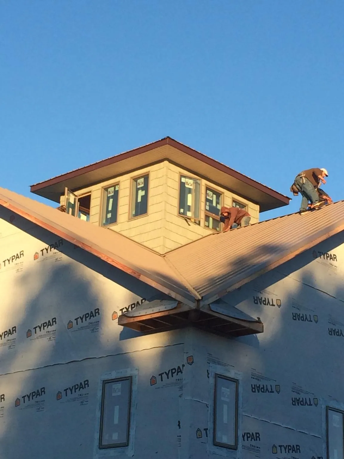 Roofers working around a rooftop cupola on a new metal roof at sunset — Roof Waterproofing in Cumberland Furnace by Roofing Brothers